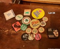 Overview of vintage pins with various slogans and designs laid out on wooden surface.