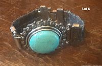 Front view of vintage silver metal mesh bracelet with large oval turquoise stone and decorative silver frame.
