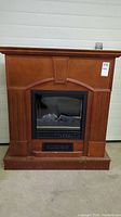 Front view of the small electric fireplace with wood finish and electric insert visible inside.