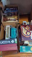 Photo showing boxes of Monopoly, multiple puzzles (250 and 300 pieces), Scrabble, NHL Checkers, card games, and other games in boxes and plastic bags.