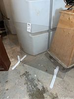 Single plexiglass panel upright on concrete floor with two white metal stands visible