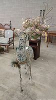 Front angle view of white woven reindeer lawn decoration with wire antlers and decorative collar.