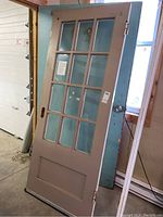 Front view of the solid wood door showing the 12 glass panes, metal knob, and hinges.