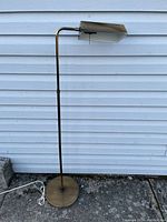 Full view of the adjustable metal floor lamp showing the base, pole and angled shade with pull chain.