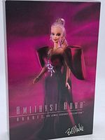 Photo of the original box showing the Amethyst Aura Barbie from Bob Mackie Jewel Essence Collection against a purple-pink background.