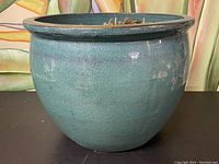 Side view of round ceramic planter showing teal blue glaze and wide rim
