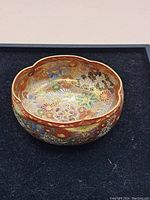 Top view showing the scalloped rim and detailed gold floral pattern inside the dish with red border.