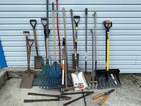 Full view of large lot of assorted yard tools lined up against house wall showing all items