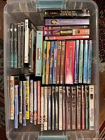 Top view of all DVDs arranged inside a clear plastic container showing a variety of DVD titles and cases.
