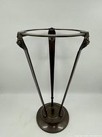 Full view of metal planter stand showing the lion head details on each leg and circular planter frame.