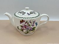 Front view of the tea pot displaying floral and butterfly artwork with handle and spout visible.
