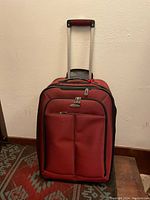 Front view of the red Samsonite suitcase showing telescoping handle and front pockets.