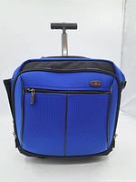 Front view of blue Victorinox carry-on showing front zippered pockets, black zipper pulls, and telescoping handle extended.
