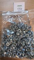 Clear plastic bag containing approximately 200 large stainless steel hex nuts with label '200 x' written on the bag.
