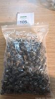 Clear plastic bag filled with numerous blackened stainless steel flanged hex head bolts, labeled with quantity '250x'.