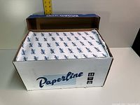 Open case showing packed copy paper reams with Paperline branded wrapping inside a cardboard box.
