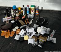 Full overview of the lot showing multiple shoe care products including sprays, creams, brushes, foot rollers, cloths, and applicators arranged on a black surface.