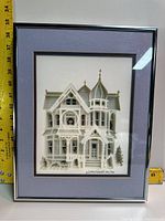 Front view of framed artwork measuring about 38 cm tall including frame showing detailed paper cut Victorian house with signature and edition number.