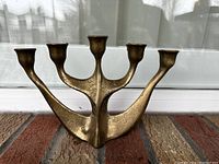 Front view of the metal candelabra displaying its five holders and unique curved design