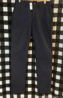 Front view of new dark-colored men's pants hanging on a hanger