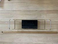 Top-down photo of the gold metal framed bathtub rack with marble tray placed next to a measuring stick for scale.