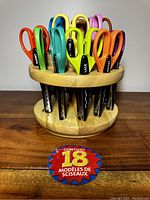 Front view of 18 Fiskar paper edger scissors in revolving wooden carousel stand, showing colorful handles and patterned blades.