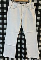 Front view of men's white INC pants hung on hanger showing pockets, button, and waistband size tag