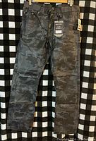 Photo showing the full front view of new black camo slim straight men's pants with tags.