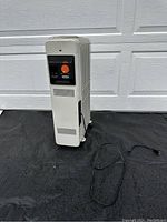 Full view of white vertical DeLonghi oil heater showing its general condition, power cord, and fins.