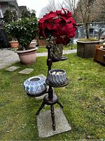 Photo of the wooden plant stand holding all three planters with flowers, shown outdoors on grass.