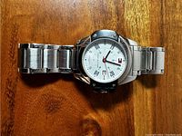 Front view of Tommy Hilfiger watch, showing white face with silver Roman numerals and logo.