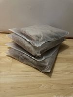 Four bath mats stacked in translucent packaging bags showing their thickness and plush texture.