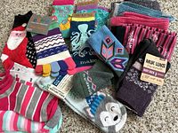 Photo showing the full lot of ladies socks in various colors and styles, some with tags visible including Muk Luks, Karma, Bombas.