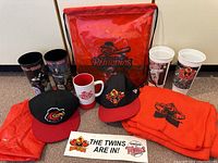 Photo of lot showing two caps, coffee mug, blanket, sticker, string bag and two white cups