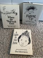 Three hardcover books by Shel Silverstein shown upright on carpeted floor, with dust jackets featuring distinct black and white drawings and titles.