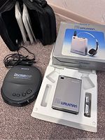Photo showing Sony Discman ESP portable CD player, FM Walkman stereo receiver in original box with battery, black carrying case with CD sleeves, and audio cable.