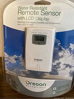 Front of sealed Oregon Scientific remote sensor in packaging showing LCD display and product info