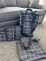 Three assorted Thirty-One bags: a tote, a lunch box, and a smaller organizer pouch, all in dark gray with white plaid pattern.