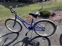 Blue women's Trek Town & Country bicycle full side profile outdoors on pavement with grass in background.