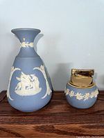 Full view of both Wedgwood blue jasperware vase and matching table lighter on wooden surface