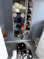 Photo showing hanging fabric storage unit containing various yarn skeins and balls in multiple colors and textures