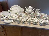 Full set displayed including plates, bowls, teapot, cups and saucers