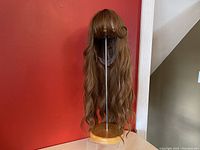 Front view of the long wavy auburn red synthetic wig on a stand showing the bangs, length, and wavy texture.