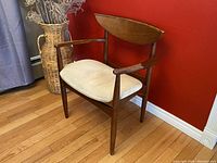 Front right angle view of the walnut mid century modern accent arm chair showing the curved backrest and cushioned seat.
