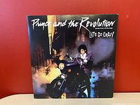 Front cover of Prince and the Revolution's Let's Go Crazy album showing Prince on a motorcycle with smoke in the background.