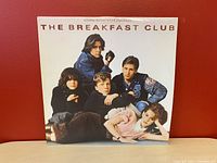 Front cover of The Breakfast Club soundtrack vinyl album, featuring photo of cast members on white background with title text.