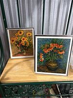 Two small framed floral art pieces side by side on a wooden surface.