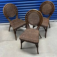 Three brown wicker chairs positioned facing forward, showing front and side views of seats and round backs. Chairs have scratches visible on the curved wooden frame portions.