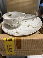 Set of 4 snack plates and 4 tea cups in original box with packing material.