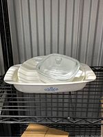 Large rectangular Corning Corelle baking dish with blue floral side design and clear glass lid on top, displayed on a metal shelf.